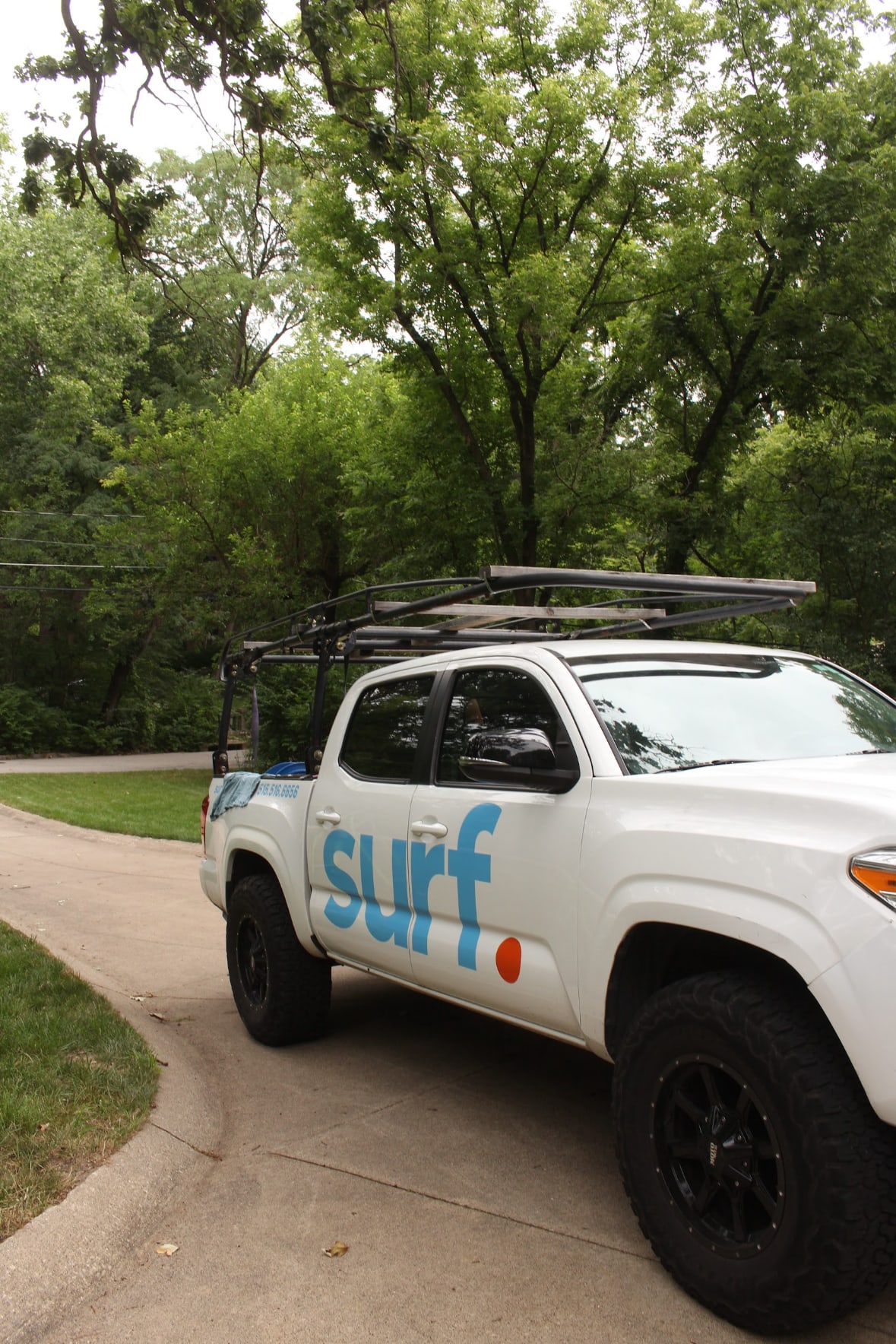 surf. truck parked in a tree-lined driveway on a job